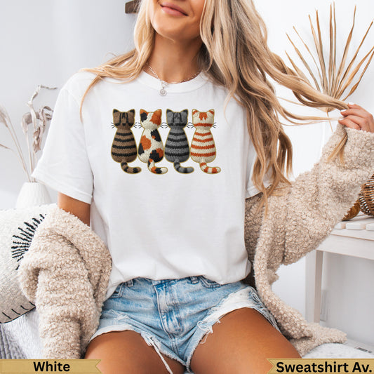 White t-shirt featuring four knitted cat designs in a row.