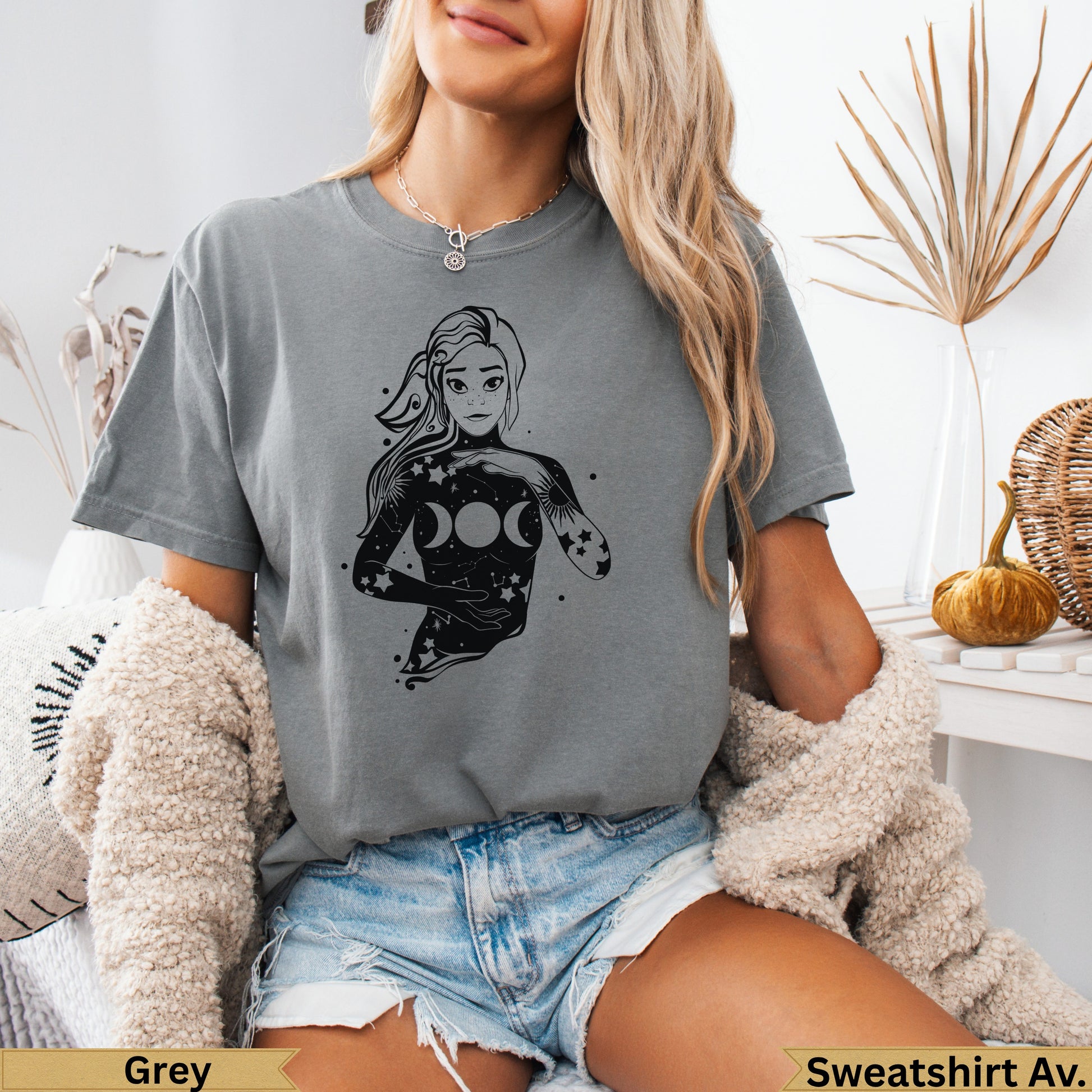 Woman with celestial moon phases design on grey graphic t-shirt.
