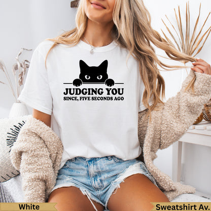 White t-shirt with black cat peeking over text that reads "Judging you since, five seconds ago".