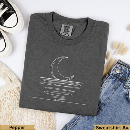 Dark gray Comfort Colors t-shirt with a white line drawing of a crescent moon and water.