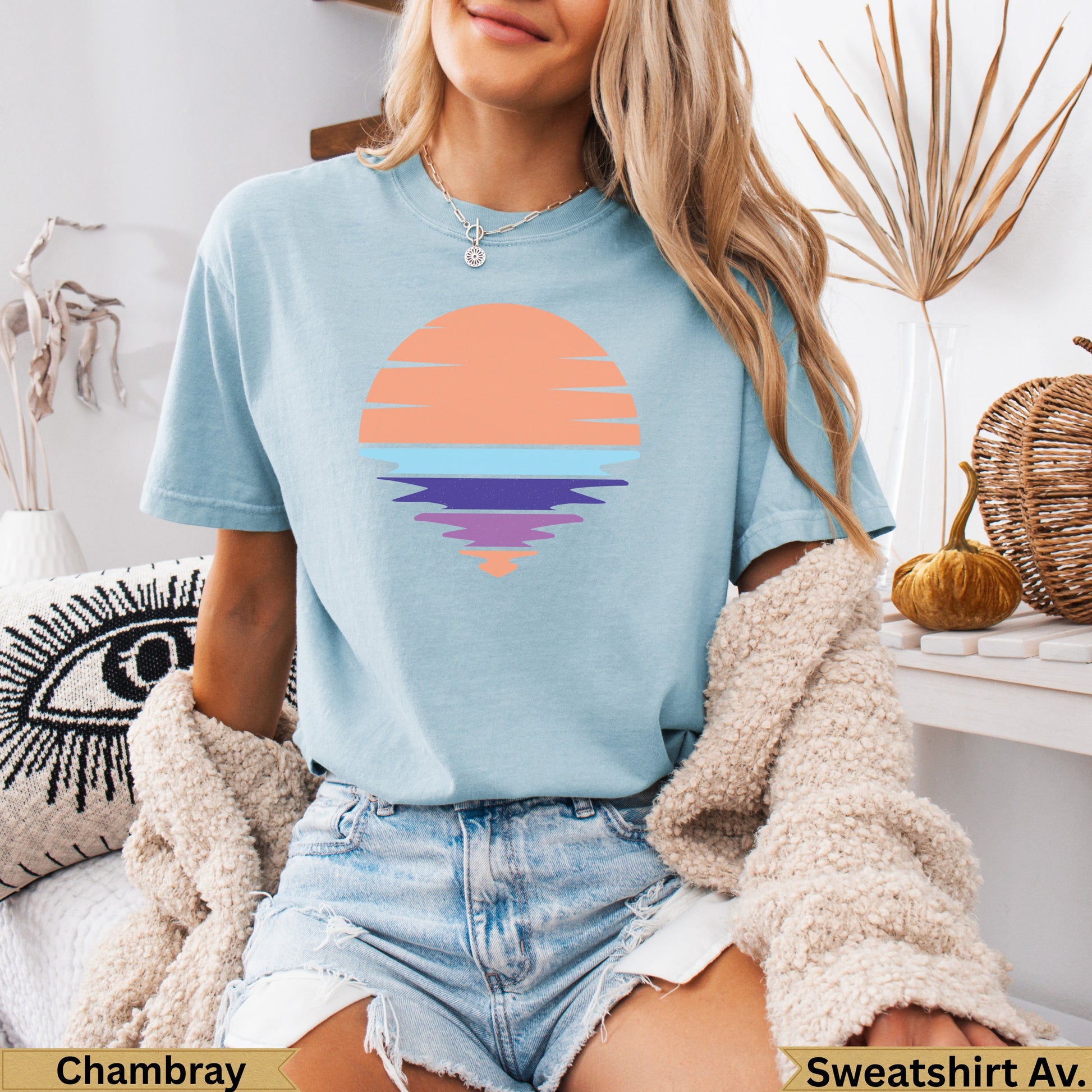 Light blue t-shirt with a graphic of a colorful sunset over water.