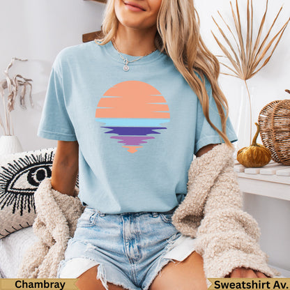 Light blue t-shirt with a graphic of a colorful sunset over water.