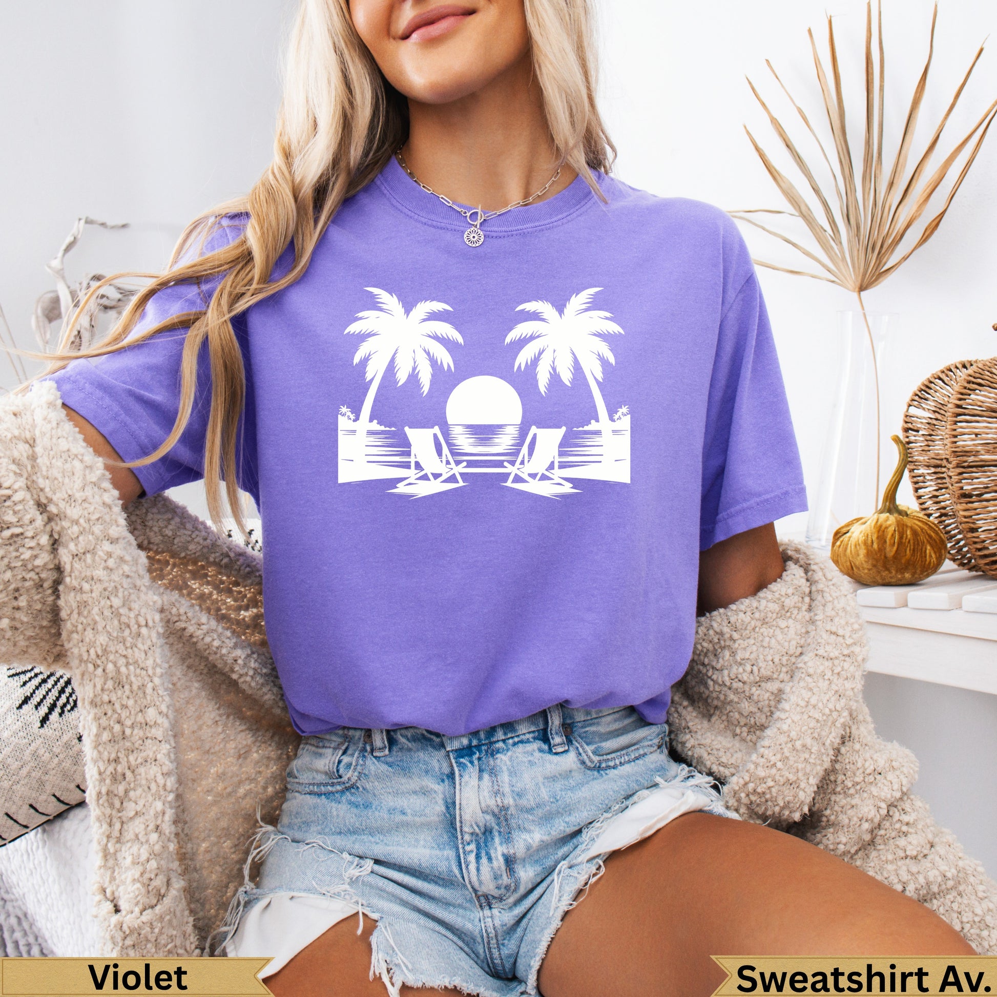 Violet t-shirt with palm trees and beach chairs graphic.