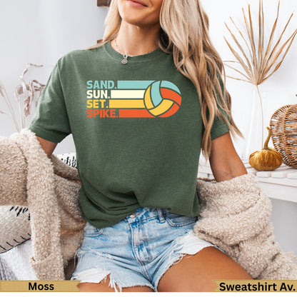 Green t-shirt with "Sand. Sun. Set. Spike." volleyball graphic.