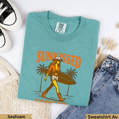 Seafoam Comfort Colors sweatshirt with "Sunkissed" text and cowgirl carrying surfboard.
