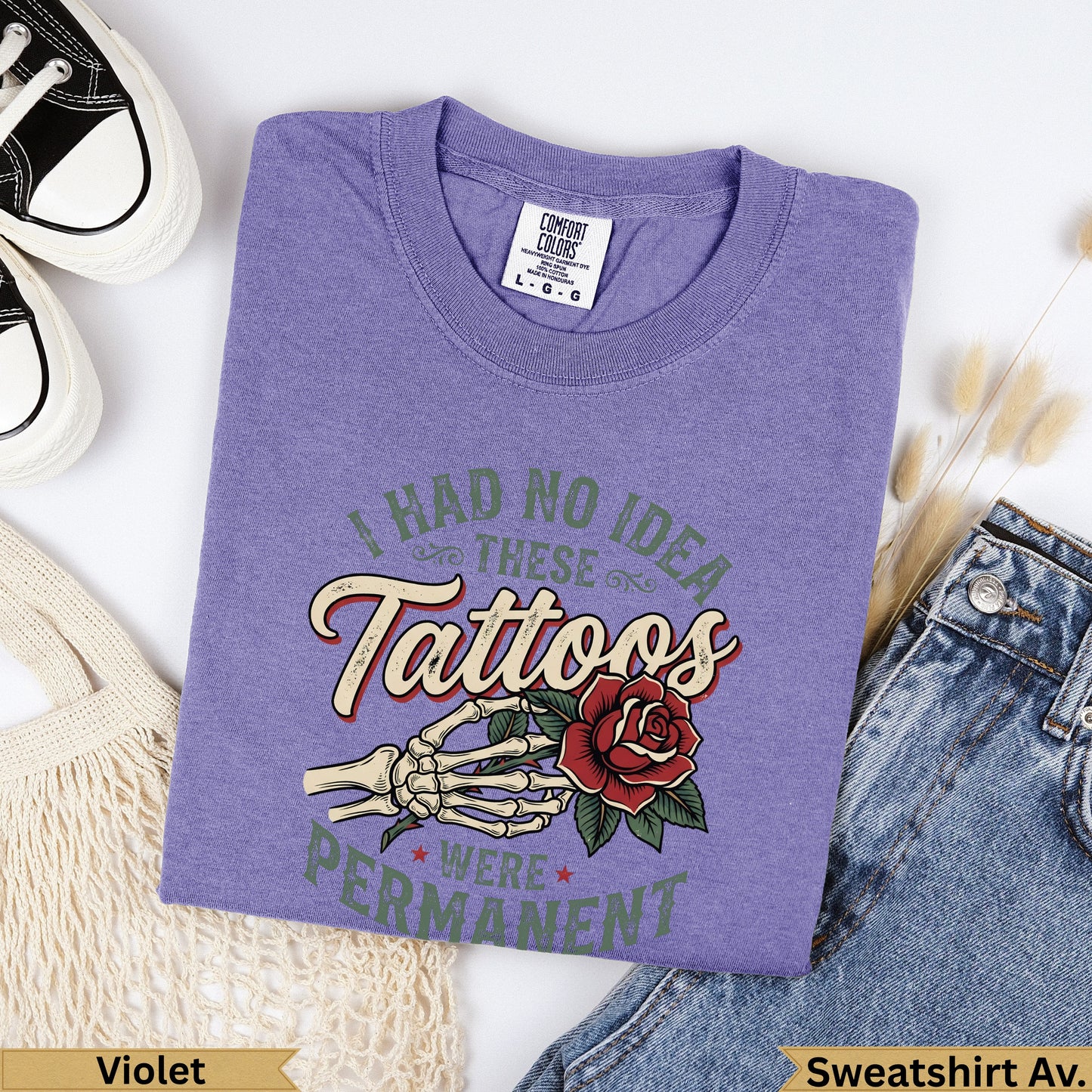 Purple t-shirt with "I had no idea these tattoos were permanent" text and skeleton hand with rose graphic.