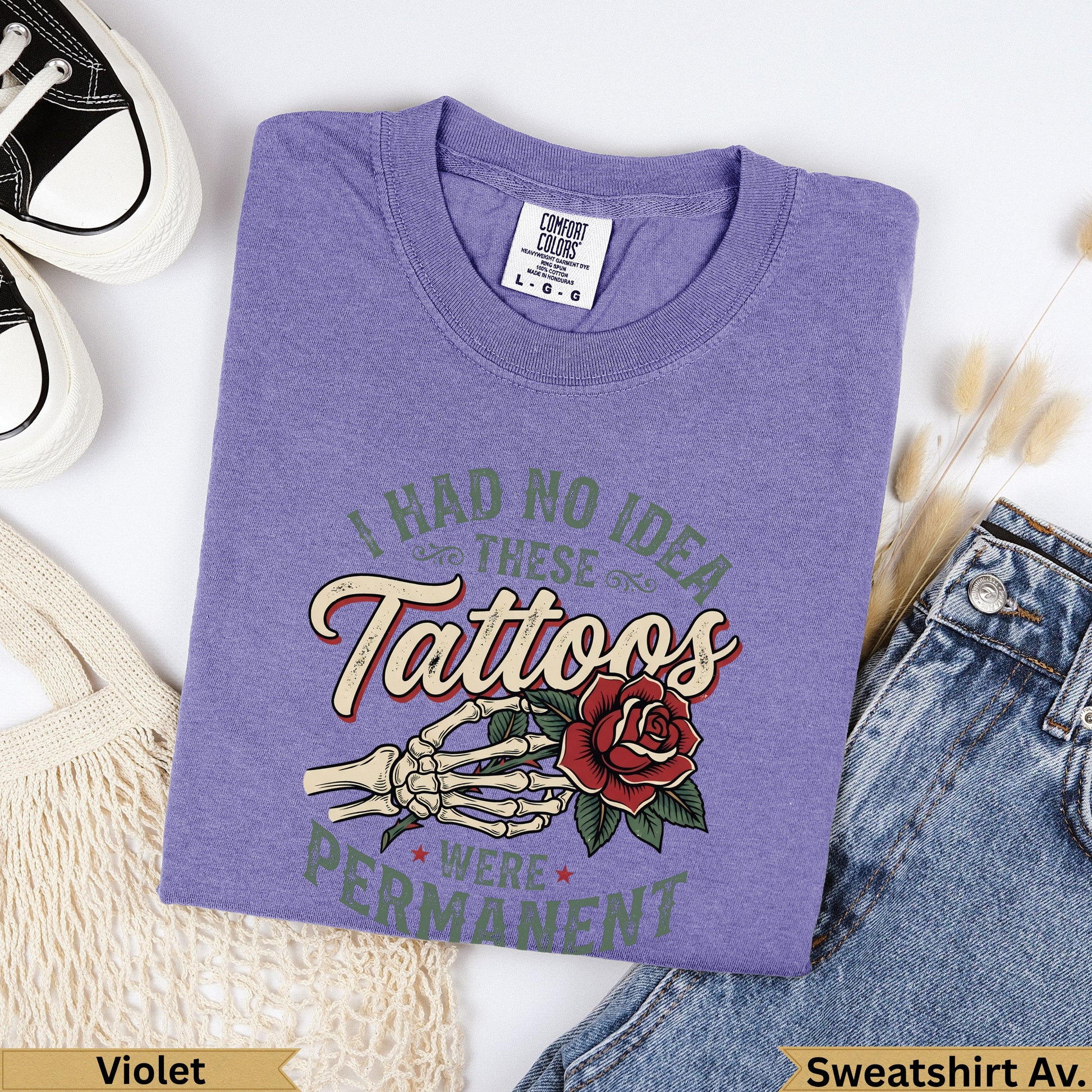 Purple t-shirt with "I had no idea these tattoos were permanent" text and skeleton hand with rose graphic.