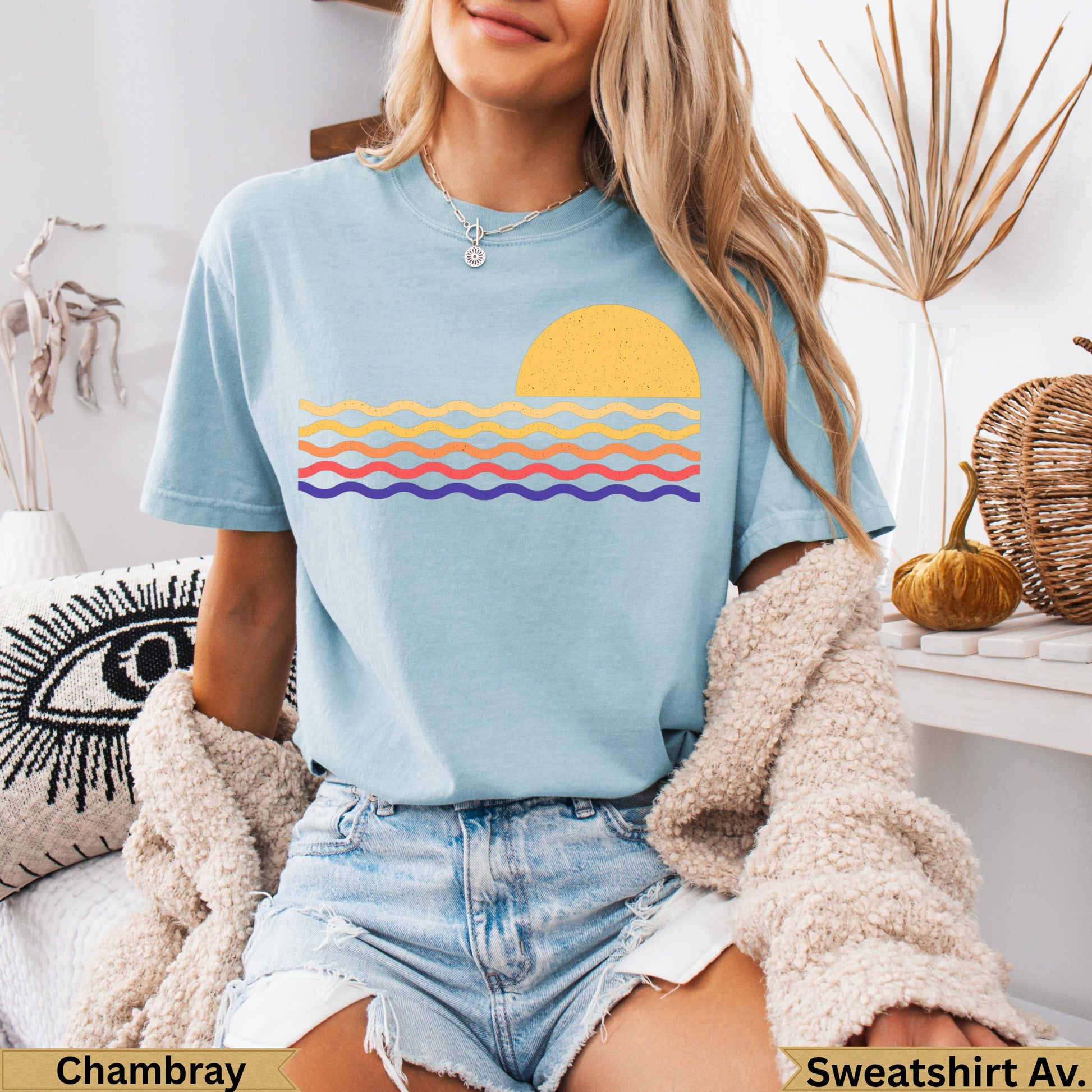 Light blue t-shirt with a yellow sun and striped waves graphic.
