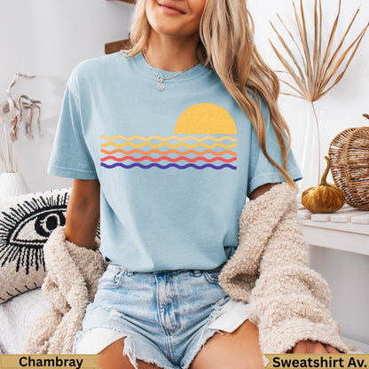 Light blue t-shirt with a yellow sun and striped waves graphic.