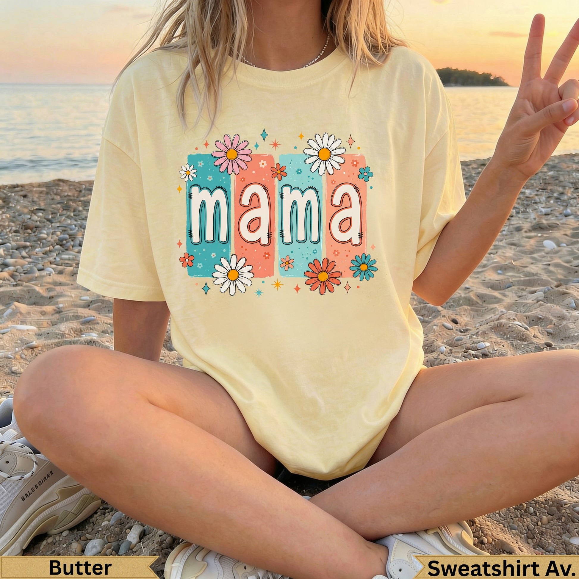 Yellow t-shirt with "mama" in colorful floral letters on a beach.