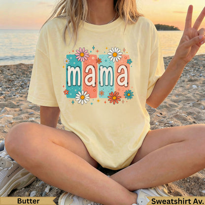 Yellow t-shirt with "mama" in colorful floral letters on a beach.