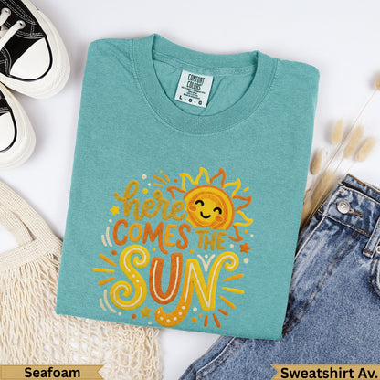 Teal Comfort Colors t-shirt with "Here Comes The Sun" sun graphic.