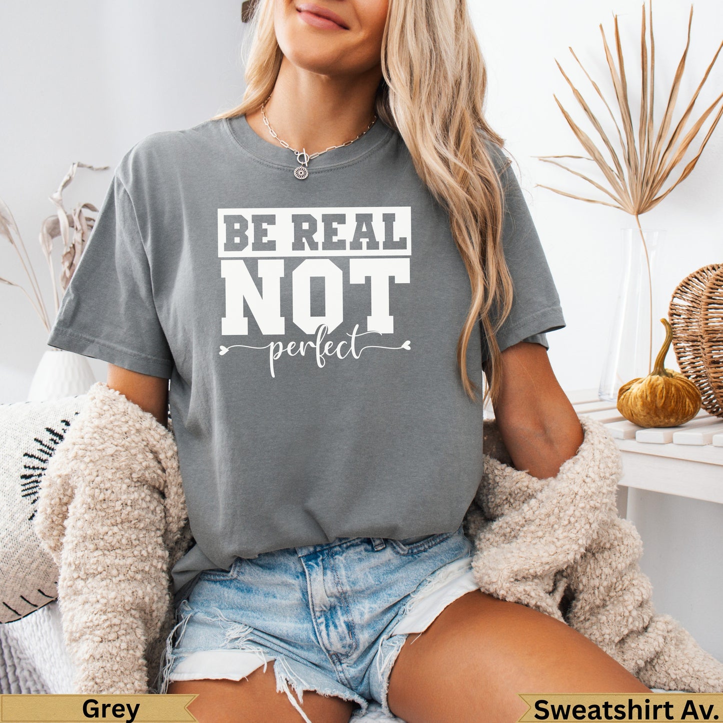 Grey graphic t-shirt with "BE REAL not perfect" text, worn by a model.