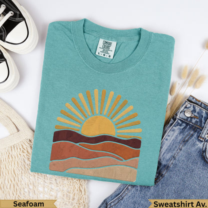 Teal Comfort Colors sweatshirt with sun and layered earth tones, labeled Seafoam.