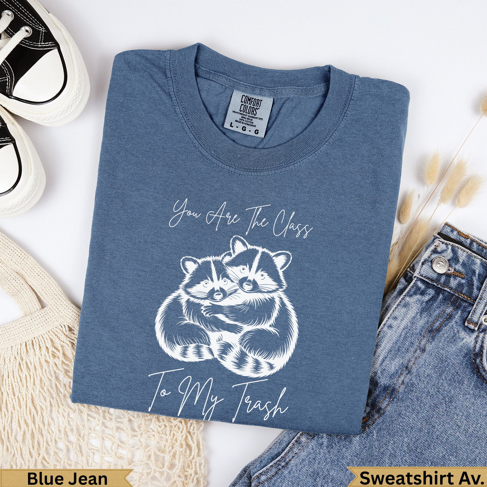 Blue Jean comfort colors sweatshirt with white graphic of two raccoons hugging.