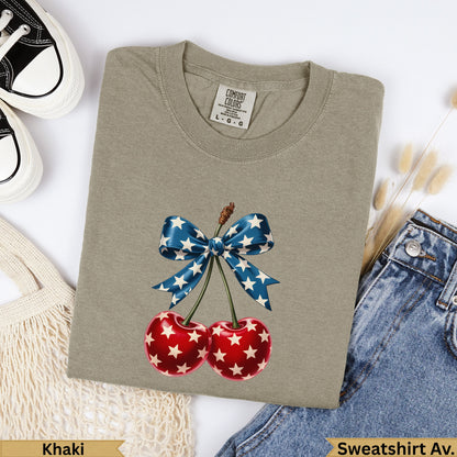 Khaki sweatshirt with a red cherry graphic and a blue star-spangled bow.