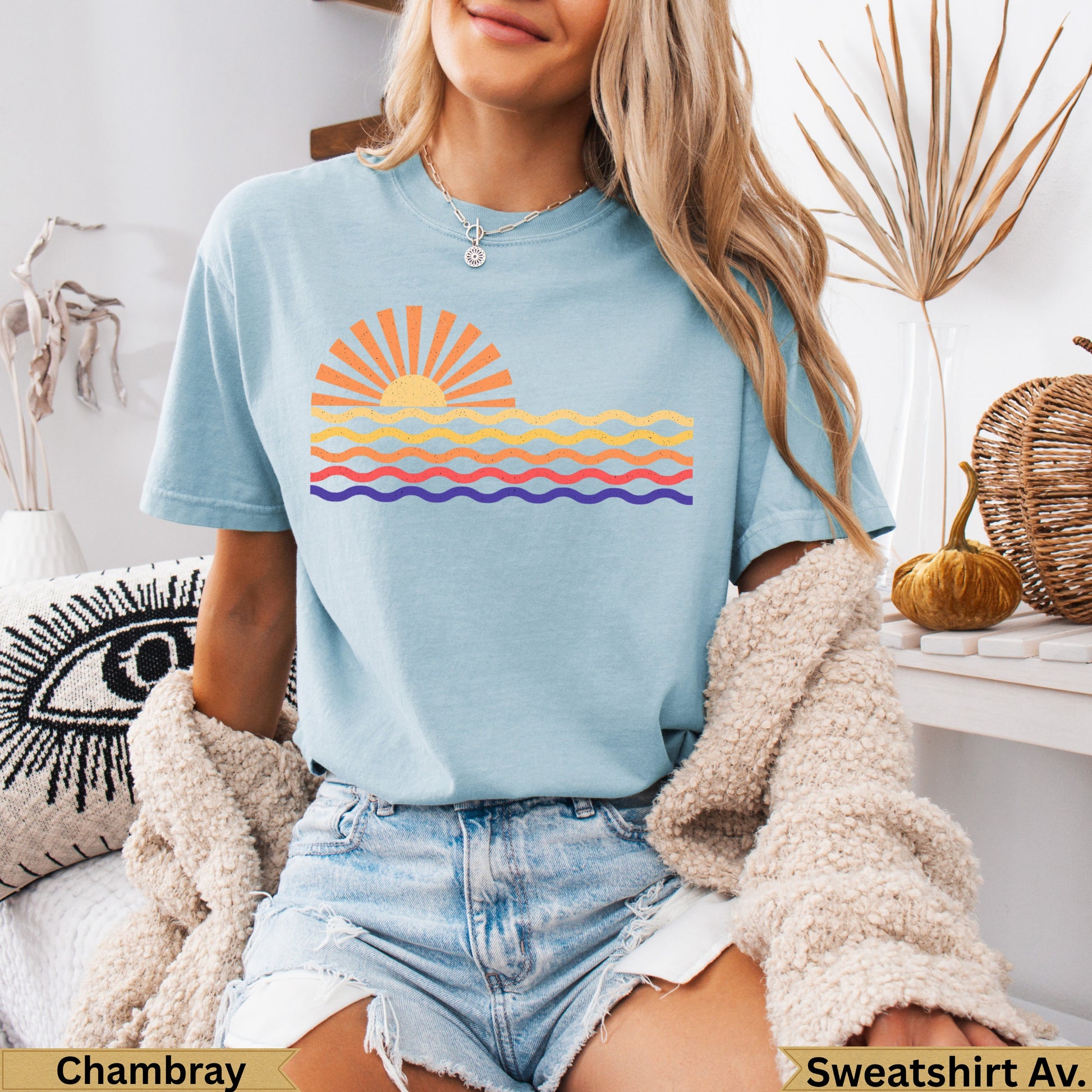 Light blue t-shirt with a stylized sun and wavy lines design.