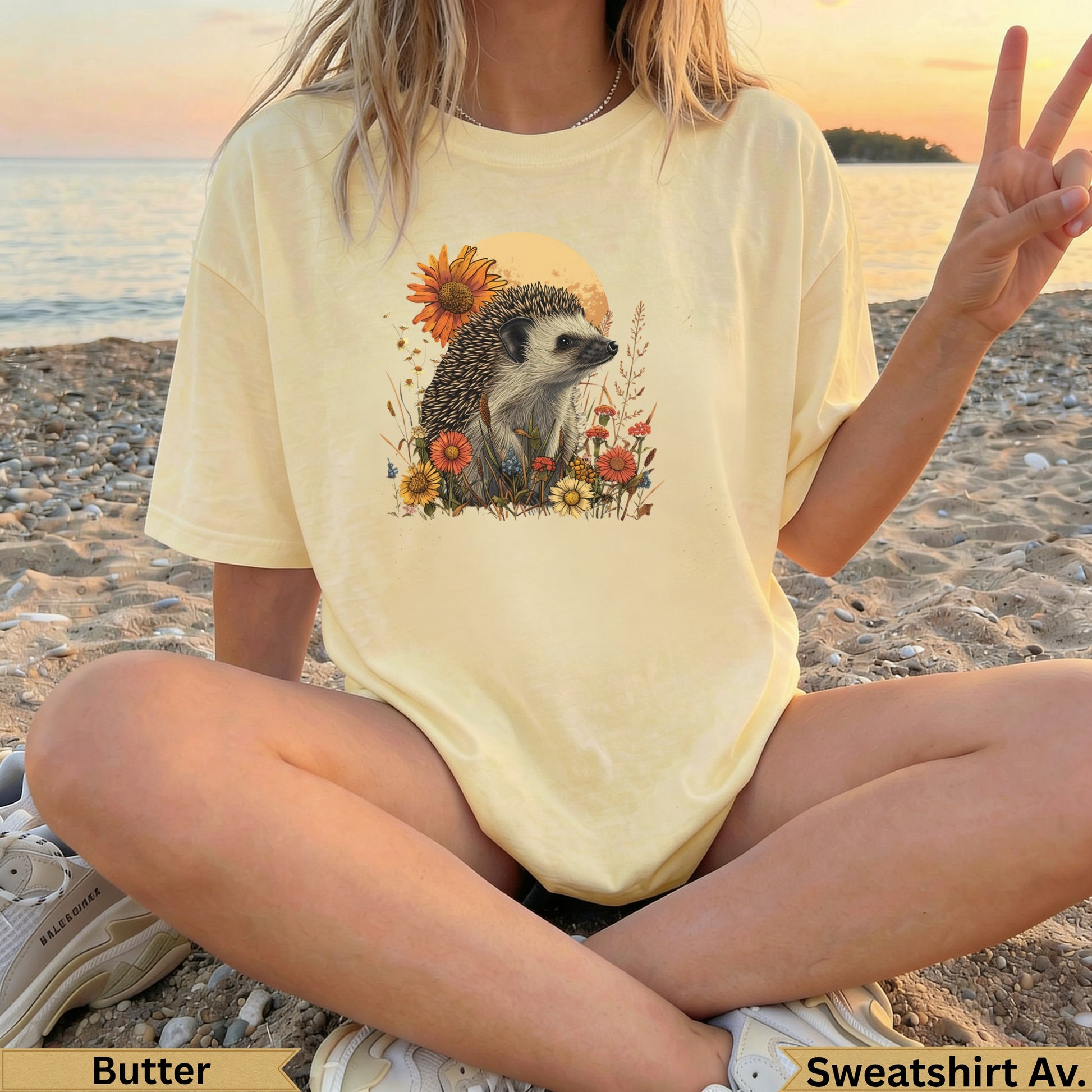 Yellow t-shirt with hedgehog and floral graphic, on a person sitting on a beach.