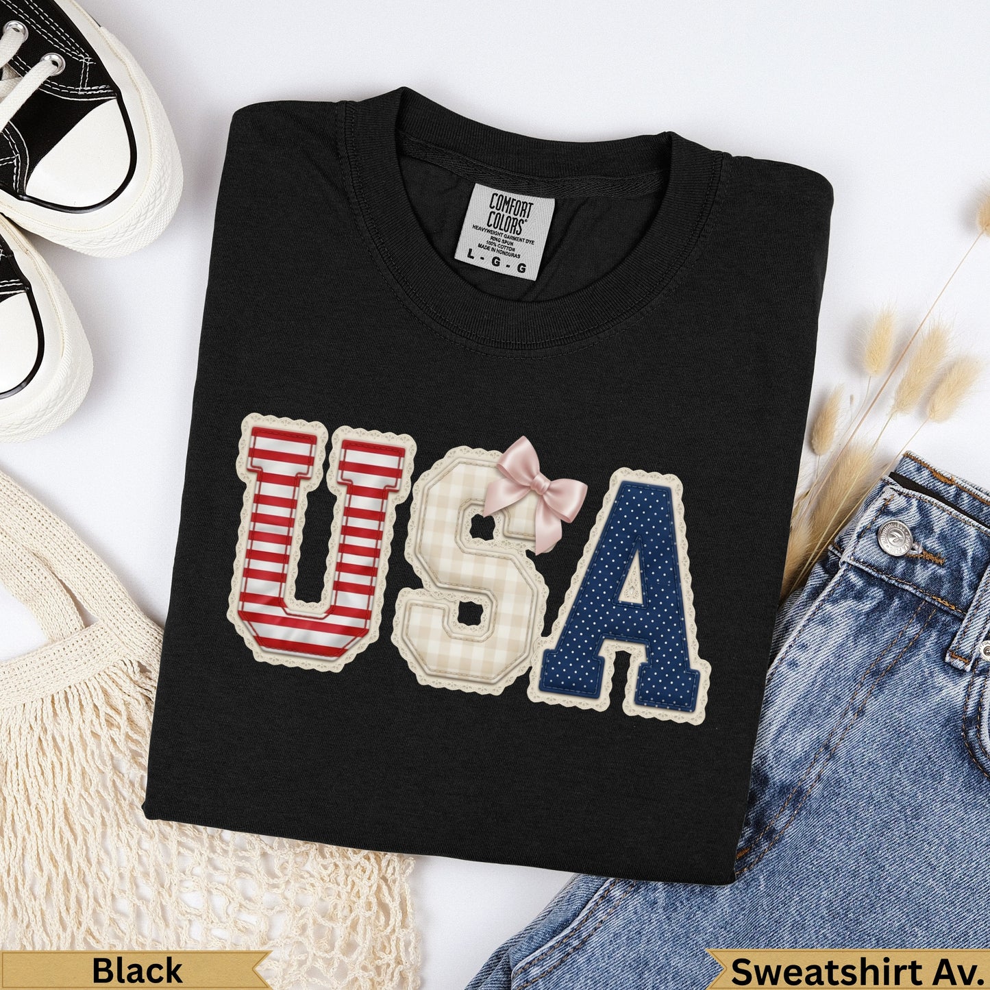 Black t-shirt with "USA" graphic made of patterned patches and a pink bow.