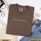 Brown Comfort Colors t-shirt with "snacks, chaos, repeat" text, with jeans and shoes.