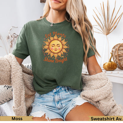 Green t-shirt with sun graphic and "Eat Plants Shine Bright" text.
