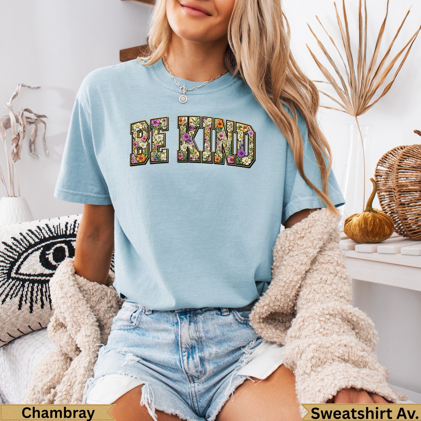 Light blue t-shirt with "BE KIND" in floral text, worn by a model.