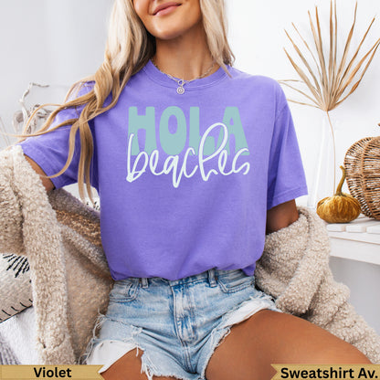 Purple t-shirt with "Hola beaches" text, worn by a woman.