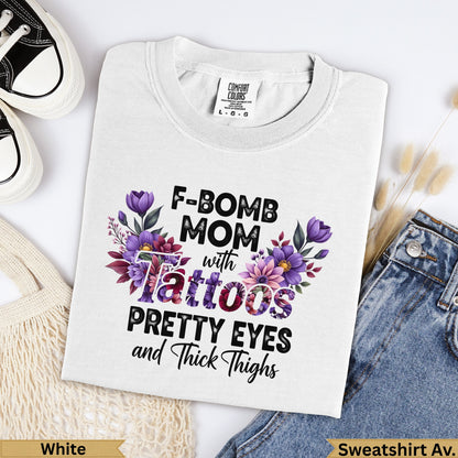 White Comfort Colors sweatshirt with "F-Bomb Mom with Tattoos Pretty Eyes and Thick Thighs" graphic.