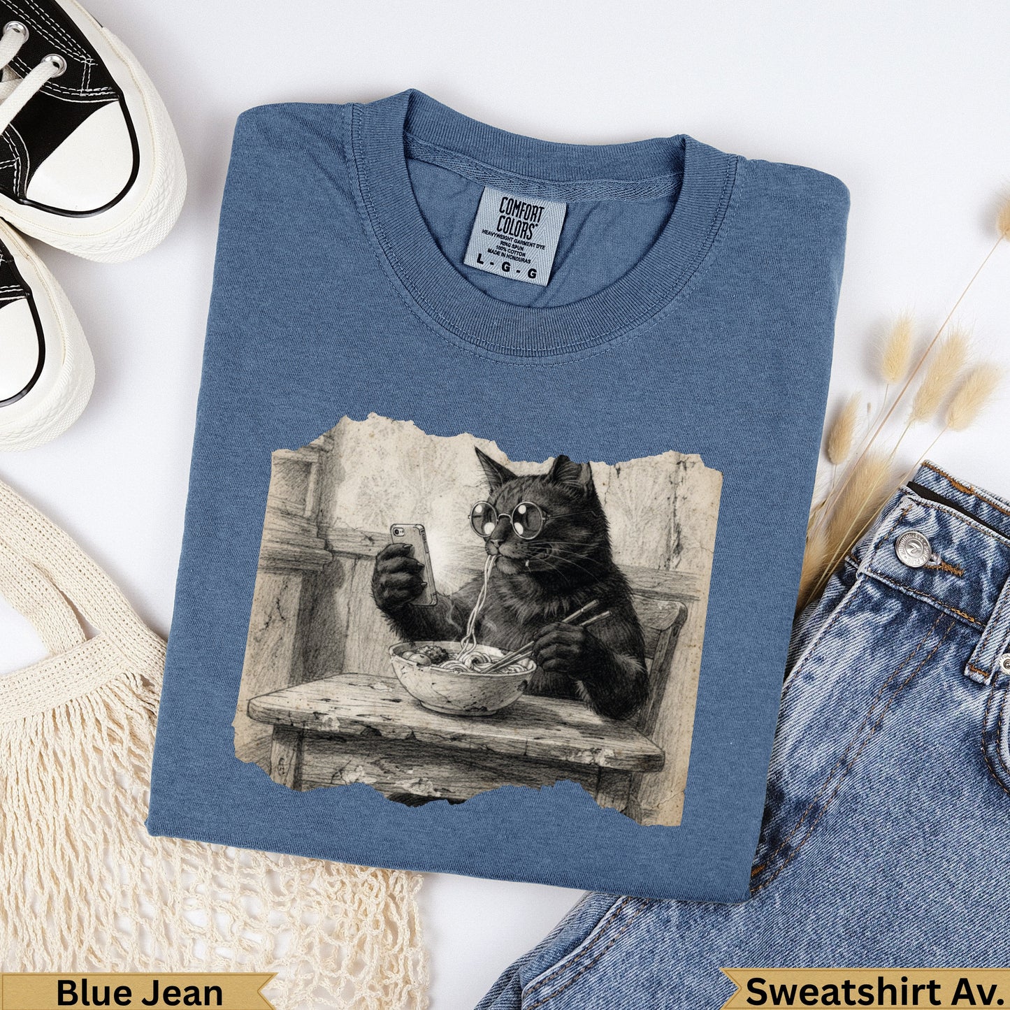 Cat wearing glasses eating ramen from a bowl, on a blue t-shirt.