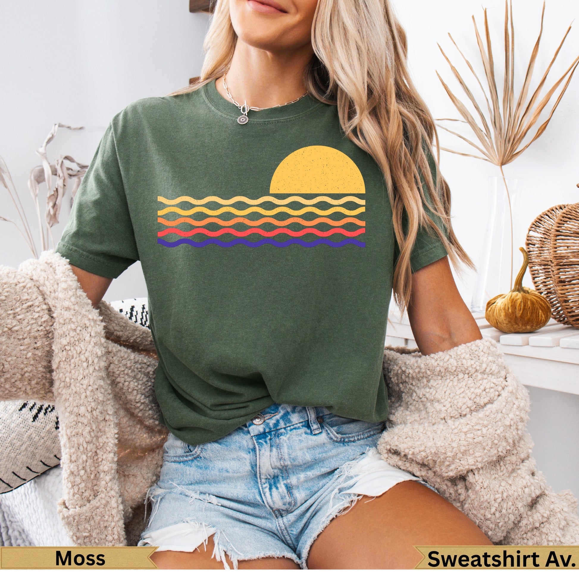 Olive green t-shirt with a retro sunrise and wavy lines graphic.