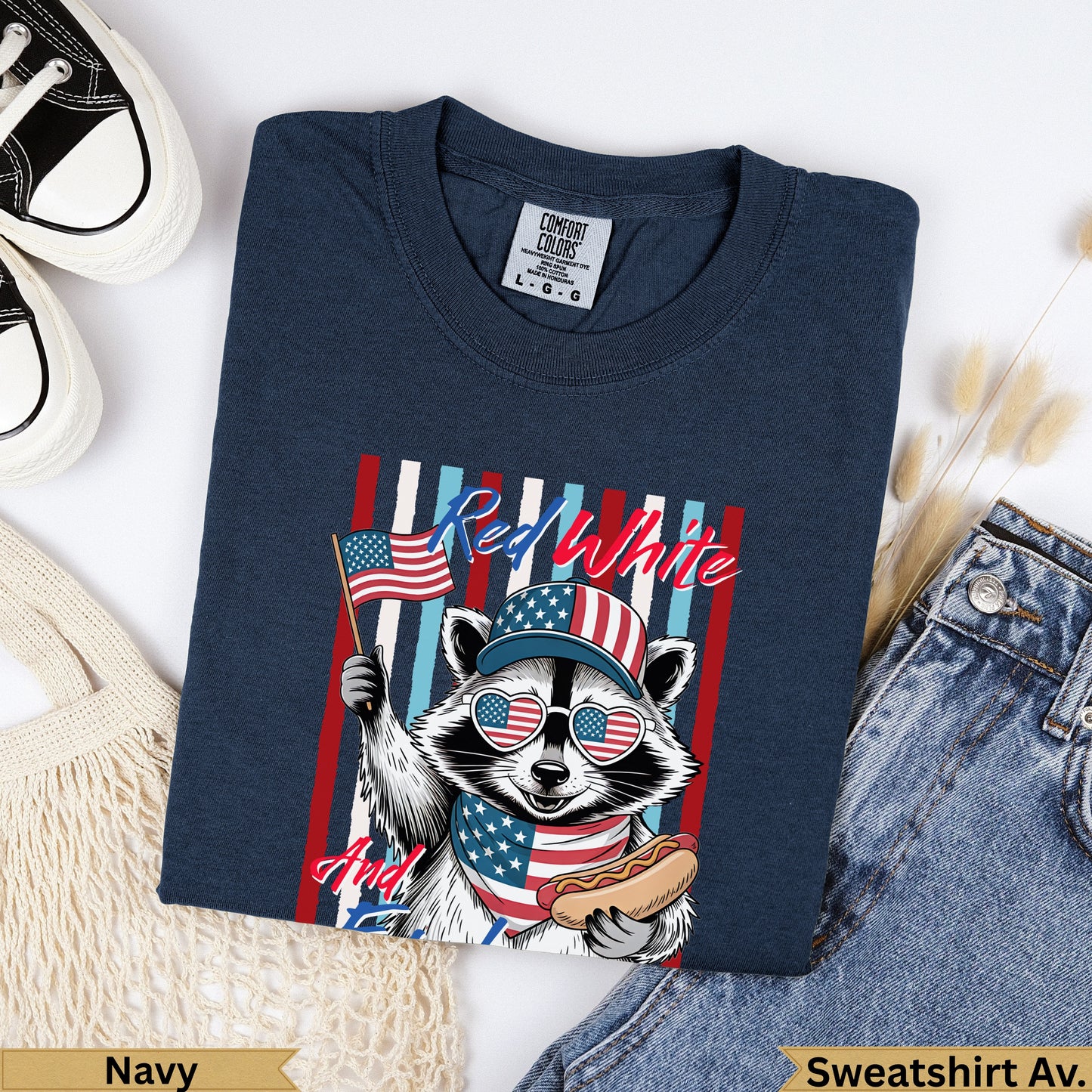Navy sweatshirt with raccoon in sunglasses holding American flag and hot dog.
