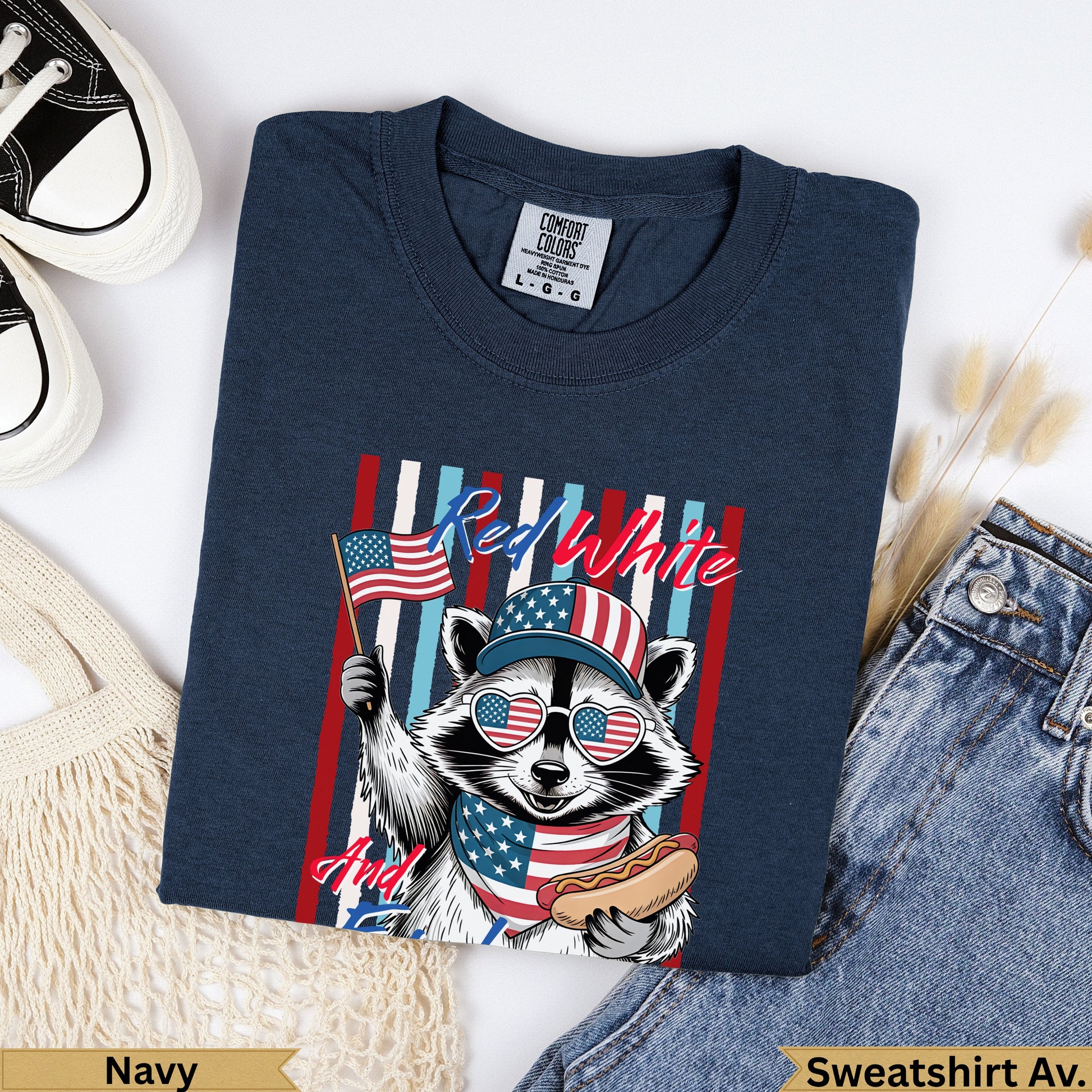 Navy sweatshirt with raccoon in sunglasses holding American flag and hot dog.