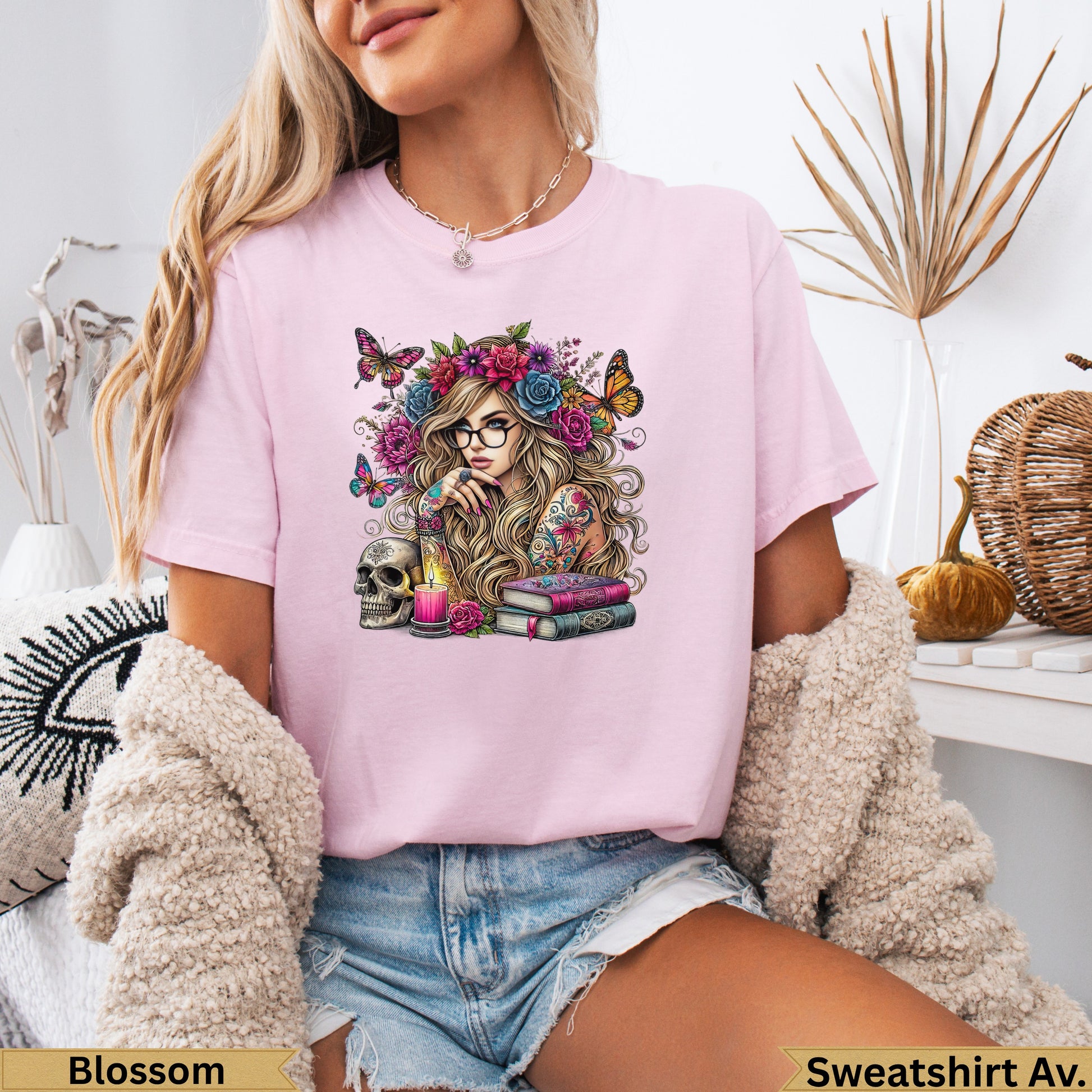 Woman with tattoos, glasses, butterflies, skull, and books on pink t-shirt.