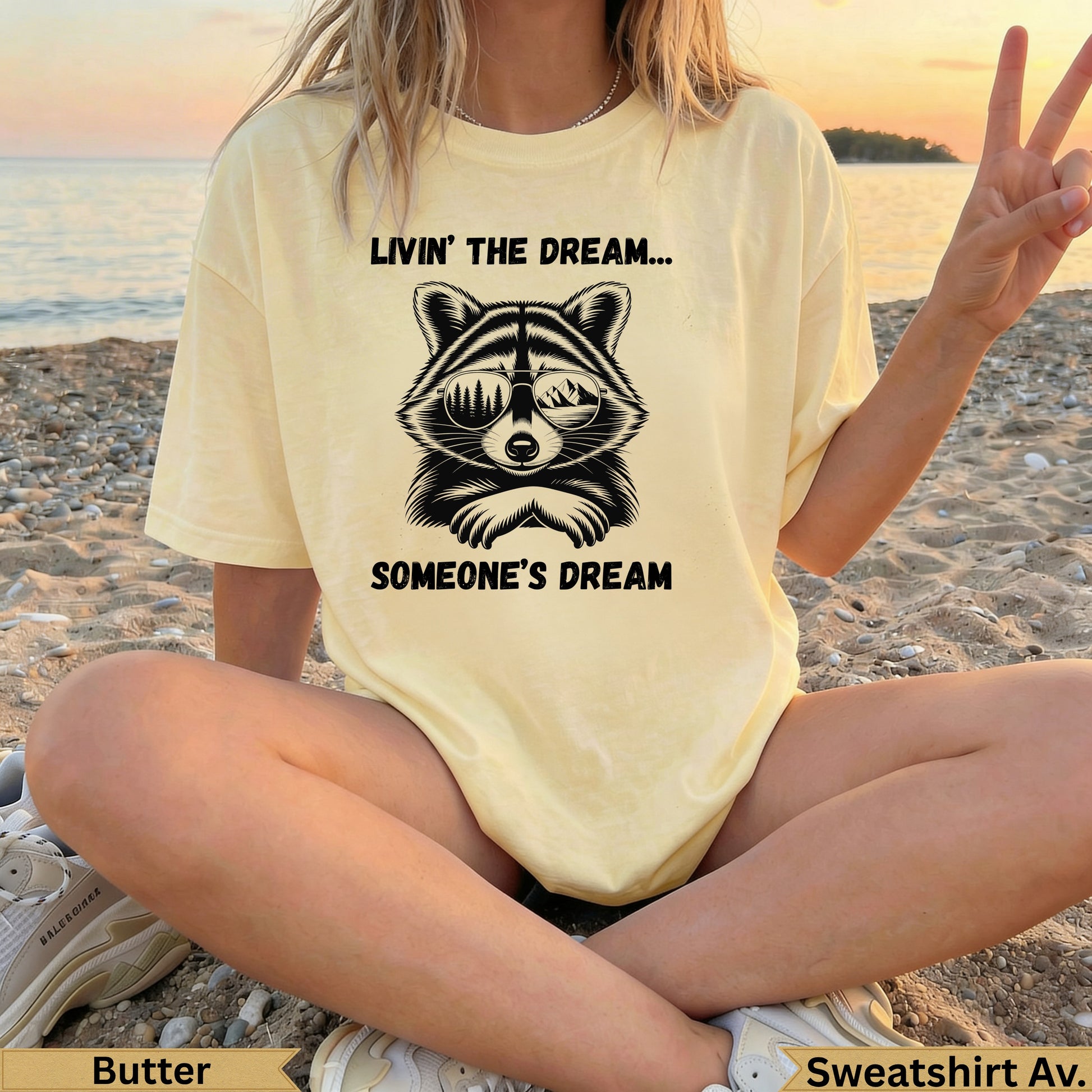 Yellow t-shirt with sunglasses-wearing raccoon and text "Livin' the dream... Someone's dream".