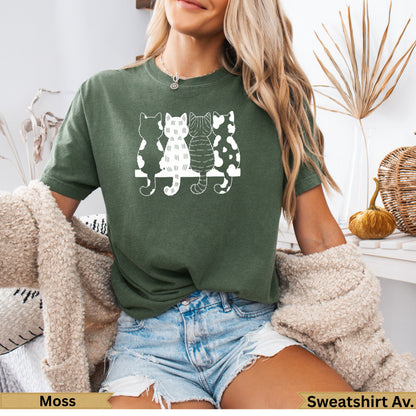 Woman wearing olive green t-shirt with three black and white cartoon cats.
