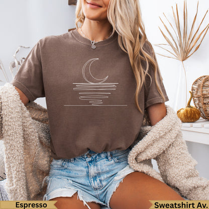 Brown crewneck t-shirt with white crescent moon and water line graphic.