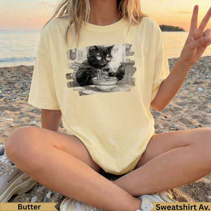 Light yellow t-shirt with black cat wearing glasses eating noodles graphic.