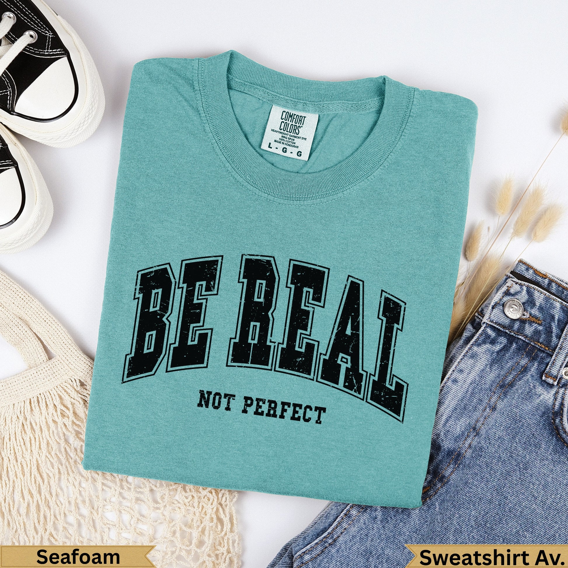 Teal Comfort Colors "BE REAL NOT PERFECT" graphic t-shirt with jeans.