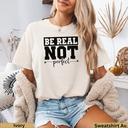 Cream sweatshirt with "BE REAL NOT perfect" graphic, worn by a woman.