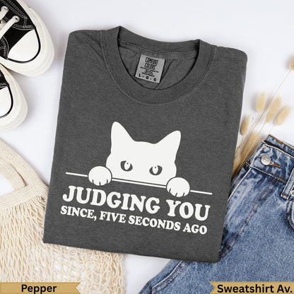 Dark grey t-shirt with white cat graphic and "Judging you since, five seconds ago" text.