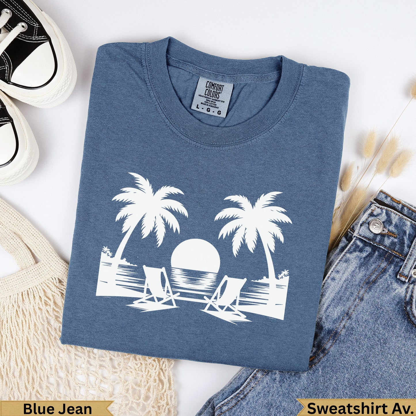 Blue denim t-shirt with white palm trees, sun, and chairs graphic.