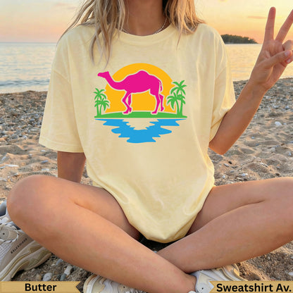 Light yellow graphic t-shirt with camel, palm trees, and water illustration.