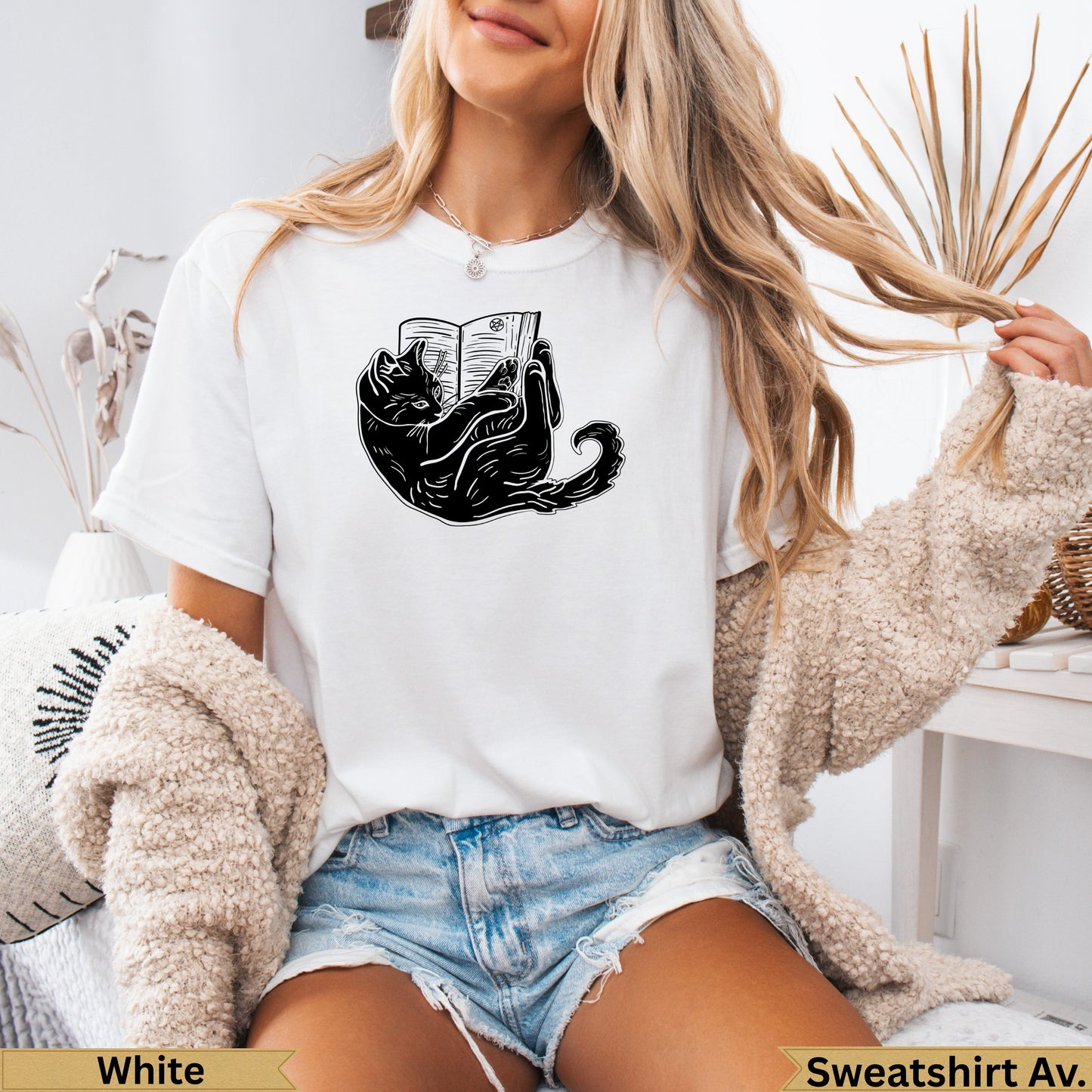 Black cat illustration on white t-shirt, reading a book.