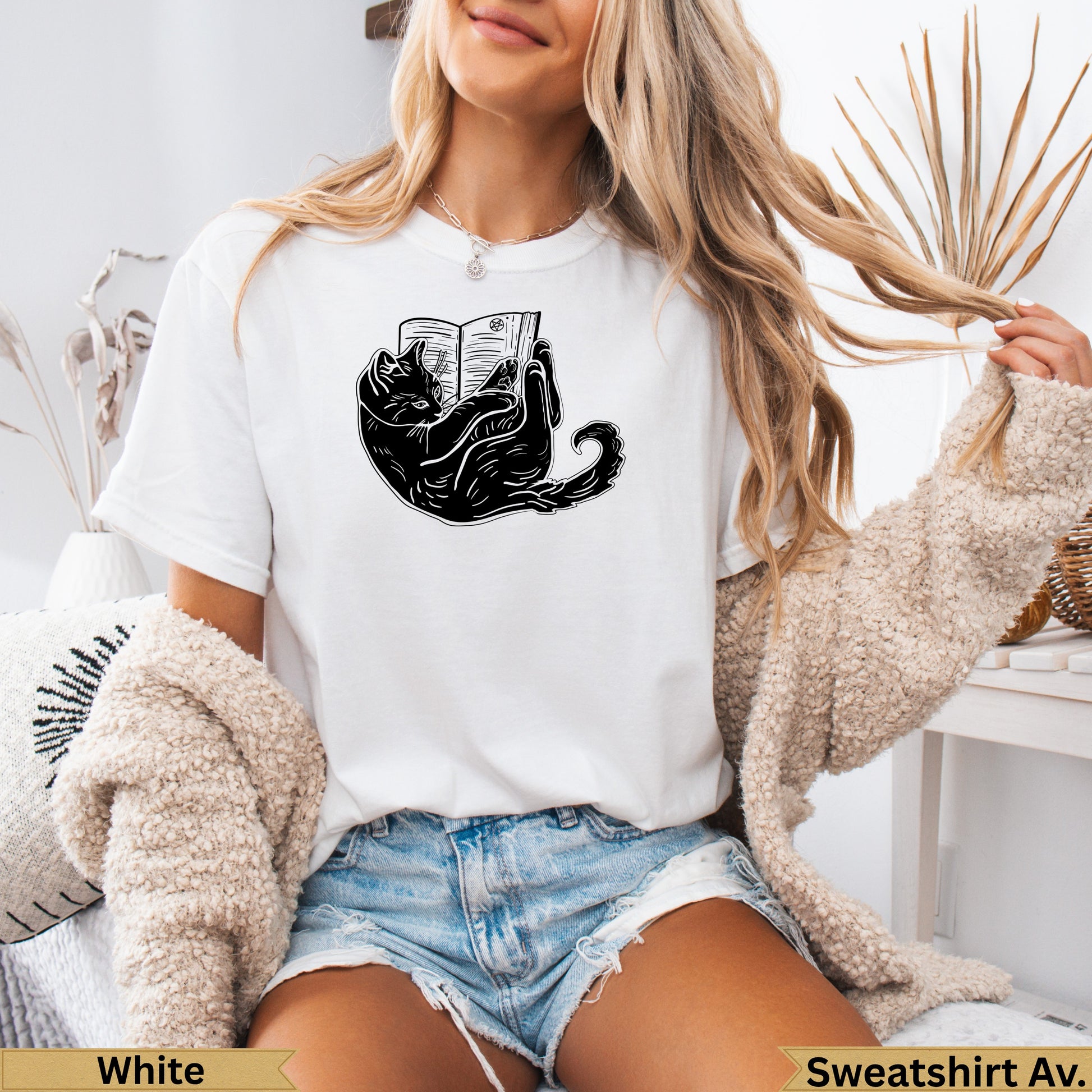 Black cat illustration on white t-shirt, reading a book.