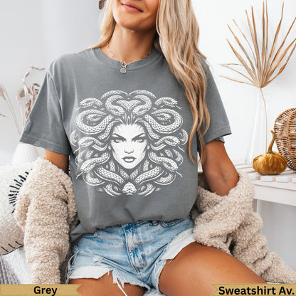 Grey t-shirt featuring a Medusa graphic with snakes for hair and denim shorts.