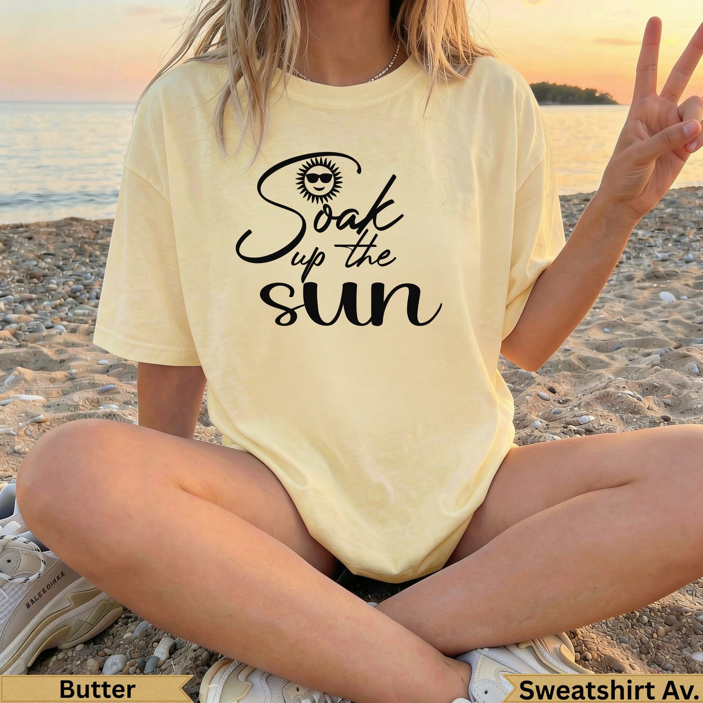 Woman wearing light yellow "Soak up the sun" graphic t-shirt on a beach.