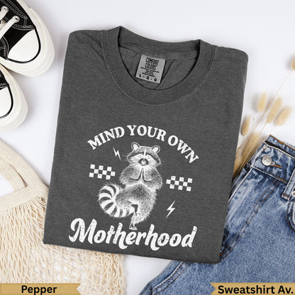 Dark grey graphic sweatshirt with "Mind Your Own Motherhood" text and raccoon graphic.