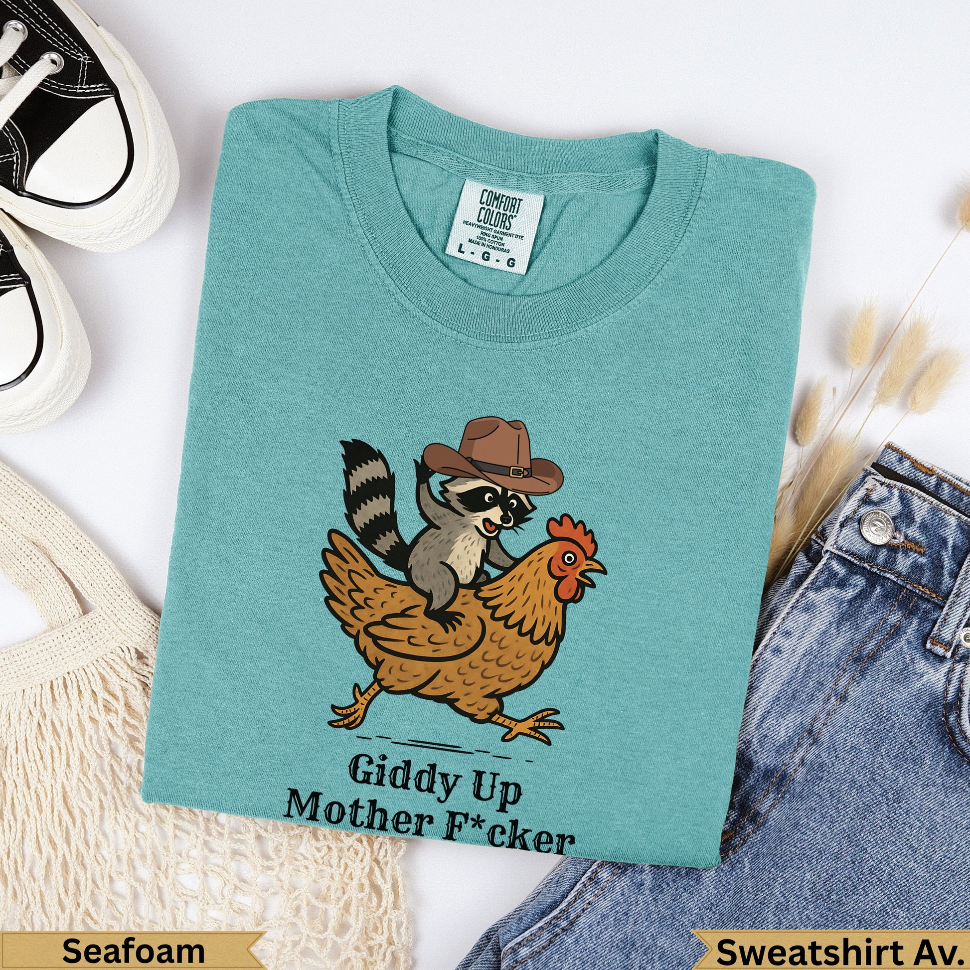 Teal sweatshirt with raccoon in cowboy hat riding a chicken, "Giddy Up Mother F*cker" text.