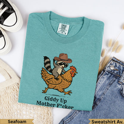 Teal sweatshirt with raccoon in cowboy hat riding a chicken, "Giddy Up Mother F*cker" text.