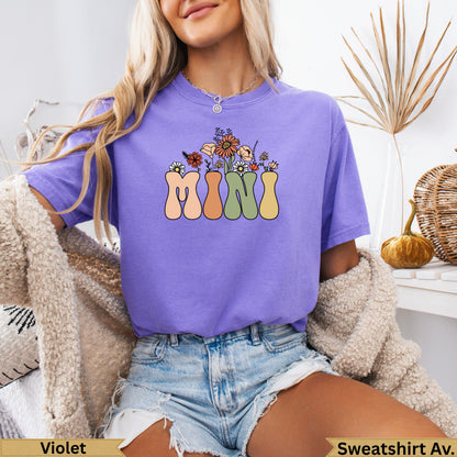 Purple t-shirt with "MIMI" in colorful, retro floral lettering.